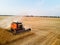 Aerial drone photo of red harvester working in wheat field on sunset. Combine harvesting machine driver cutting crop in