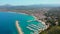 Aerial drone point of view coastal town of Javea with green mountains, turquoise bay Mediterranean Sea moored vessels in harbour,