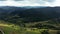 Aerial drone scenic natural landscape. Dirt road stretches on mountains ridge. Mountains are covered with coniferous forest