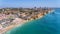 Aerial drone shot of a busy beach, amazing cliffs, vegetation and also buidlings in the background. Praia do Vau