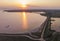 Aerial Drone Shot of colorful pink lake at sunset time with wind turbines farm on background. Cinematic landscape view