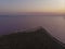 Aerial Drone Shot of colorful pink lake at sunset time with wind turbines farm on background. Cinematic landscape view