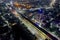 aerial drone shot with elevated metro train tracks over busy street with light trails from traffic skyscrapers on side