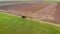 Aerial drone shot of farmer on tractor with mounted sprayer with chemicals inside turns on edge of field with barley or