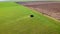 Aerial drone shot of farmer on tractor spraying crops and moving to edge of field