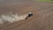 Aerial drone shot of farmer in tractor treats soil with disc harrow before sowing crops at field