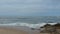Aerial drone shot flying forwards over sandy beach towards ocean on overcast day in Portugal
