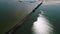 Aerial drone shot of an old mole in the sea made from wood and stones. Sea reflects sunrays