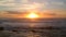 Aerial drone shot at sunset over Atlantic ocean, moving backwards with waves breaking on beach below.