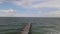 Aerial drone shot traveling over beach waves along a life guard dock back to trees on land