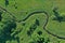 Aerial drone top down view on european green meadows and forest divided by snake like river