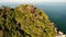 Aerial drone top view of exotic paradise tropical coastal cliff with volcanic stones covered with green jungle