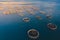 Aerial drone top view of sea fish farm cages and fishing nets, farming dorado, sea bream and sea bass, feeding the fish a forage,