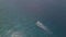 Aerial drone track view of a tourist boat traveling fast in the serene ocean.