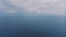 Aerial drone video footage flight over the blue sea at sunset. Beautiful clouds. Mountains in the background. Seascape.