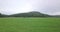 Aerial drone video moving forward in mid-air over a field flying toward a mountain