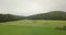 Aerial drone video panning from right to left in mid-air over a field