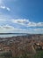 Aerial drone view of the cityscape of Lisbon with red-roofed buildings under a blue cloudy sky