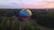 Aerial drone view of colorful hot air balloon flying over green park in small european city at summer sunrise