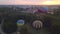 Aerial drone view of colorful hot air balloon flying over green park in small european city at summer sunrise