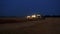 Aerial drone view of the combine harvester with lights works in night wheat fields.