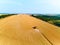 Aerial drone view: combine harvesters working in wheat field on sunset round about. Harvesting machine driver cutting