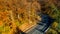 Aerial drone view of curved forest road in the mountains. Colourful landscape with rural road, trees with yellow leaves