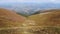 Aerial drone view of female hiker in red standing on top of mountain in summer near tent.