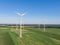 Aerial drone view of five wind power turbines, part of a wind farm, on a green field in eastern Germany near the city of Cottbus.