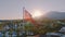 Aerial drone view of the flag flying on the roof. Sunset. Swimming pool, palm trees and mountains in the background