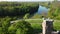 Aerial drone view flight over glade, bright green grass and stone old tower