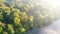 Aerial drone view flying over river with morning mist, trees yellow green leaves