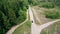 Aerial drone view following black modern van vehicle on countryside slab road between green coniferous pine trees. Car