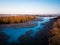 Aerial drone view of half frozen lake with island and trees - first sunrise light on tree tops - rural europe