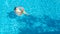Aerial drone view of little girl in swimming pool from above, kid swims on inflatable ring donut , child has fun in blue water
