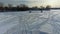 Aerial drone view moving backwards over the tracks left in the snow and going further away of camping trailers on the frozen ice