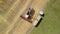 Aerial drone view. Overloading grain from combine harvesters into grain truck in field. Harvester unloder pouring