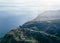 Aerial and drone view of savage landscape of forest, mountains and village with roads near the coast