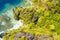 Aerial drone view of secluded beach in jungle with tropical coral reef and small sandy beach surrounded by huge cliffs