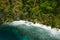 Aerial drone view of a secluded deserted tropical beach with lonely tourist boat surrounded by rainforest jungle. Cadlao