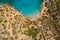 Aerial drone view of a small beach on a rocky, barren coastline and crystal clear ocean