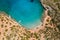 Aerial drone view of a small beach on a rocky, barren coastline and crystal clear ocean