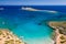 Aerial drone view of a small beach on a rocky, barren coastline and crystal clear ocean