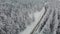 Aerial drone view of snow-covered coniferous forest and a desert road high in the mountains.