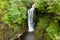 Aerial drone view of a tall waterfall in a narrow canyon surrounded by trees Sgwd Einion Gam, Wales, UK