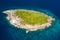 Aerial drone view of a tiny, beautiful tropical island surrounded by coral reef and clear ocean
