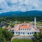 Aerial drone view of a white mosque known as Tun Khalil Mosque with Mount Ledang background at Asahan, Melaka, Malaysia.