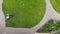 Aerial drone view of worker mowing green grass lawn with motorized or electric mower machine tool . Round shaped lawn