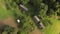 Aerial drone view of the yard with an old wooden hut, barn, stable, and haystack among green nature on mountain slope, top view