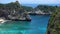 Aerial drone zooming view of tropical beach, sea rocks, turquoise ocean and palm trees. Atuh beach, Nusa Penida island